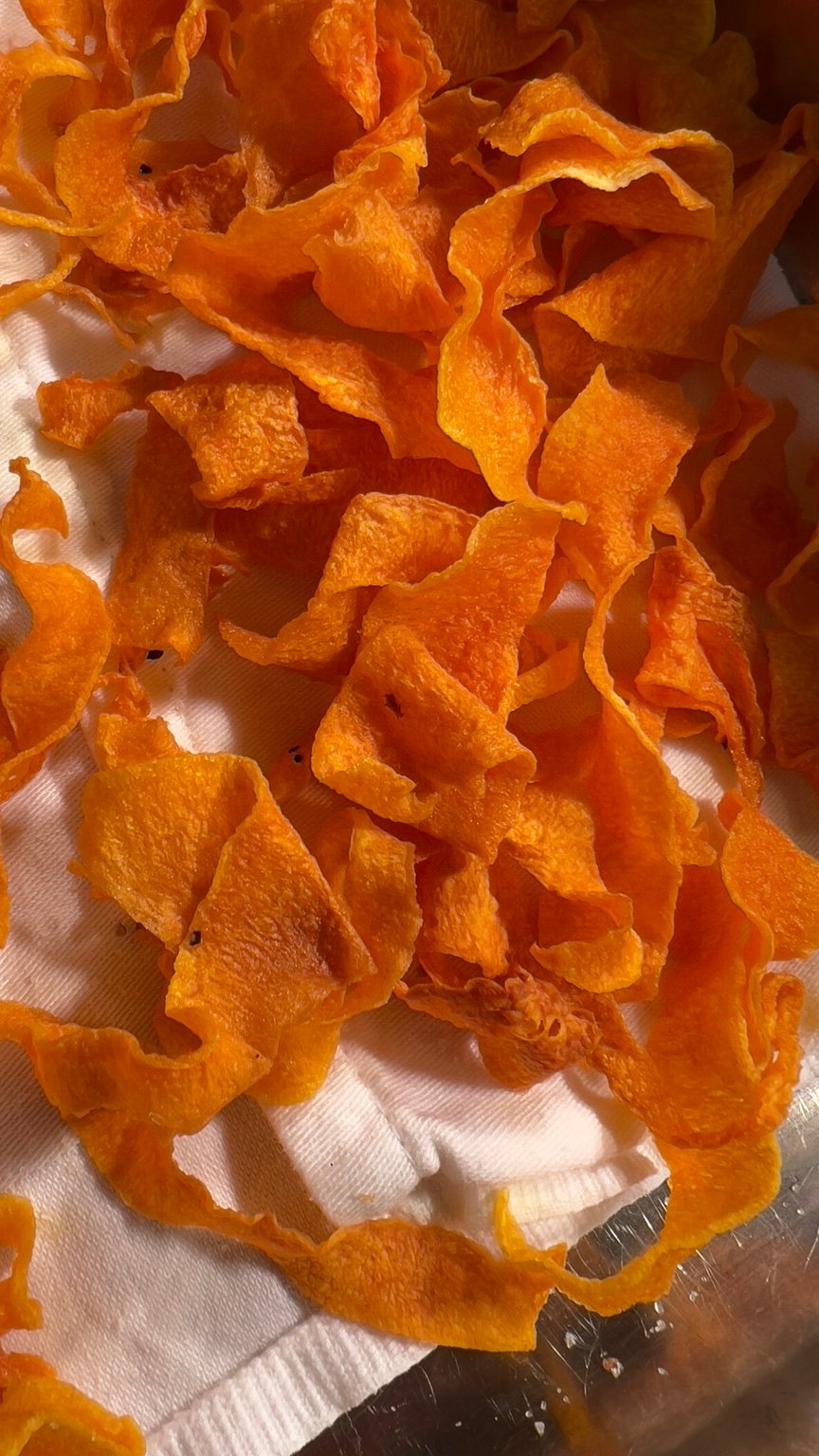Thin golden butternut squash crisps draining on kitchen paper